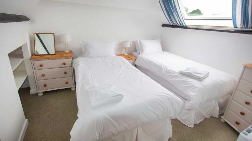 a bedroom with two beds with white sheets and a window at Shippen Cottage - Perfect for Couples or Families in Sidmouth