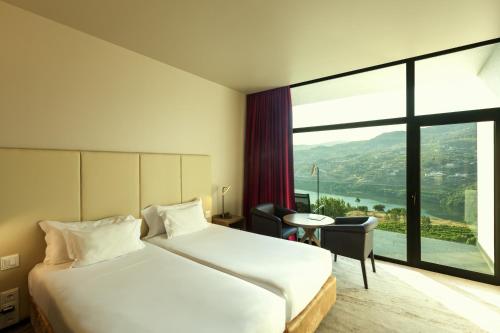 a hotel room with a bed and a large window at Douro Palace Hotel Resort & SPA in Baião