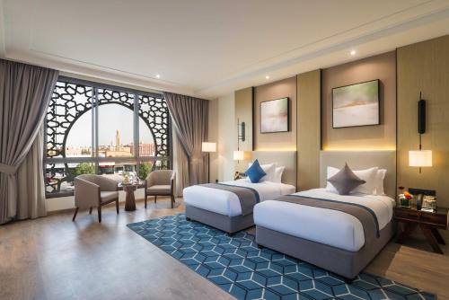 a hotel room with two beds and a large window at Braira Al Yarmouk in Riyadh