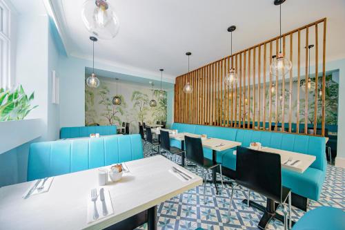 una sala da pranzo con tavoli e sedie blu di Mentone Hotel a Londra