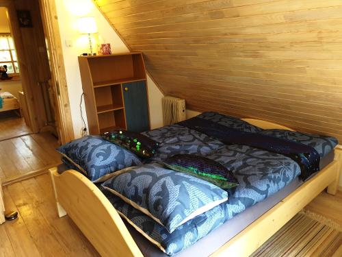 a bed in a wooden room with pillows on it at Błękitny Domek - Tleń - Bory Tucholskie in Tleń