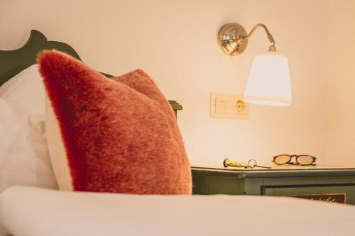 a bed with two red pillows and a lamp at Das Bräu ORIGINAL in Lofer