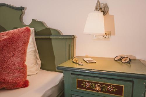 a bed with a green headboard and a table with glasses on it at Das Bräu ORIGINAL in Lofer