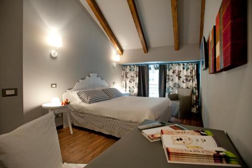 a bedroom with a bed and a table with a book at Vinoteca La Sacrestia in Alba