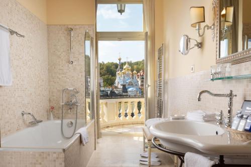 a bathroom with a tub, sink, and mirror at Savoy Westend Hotel in Karlovy Vary