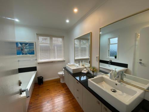 a bathroom with two sinks and a large mirror at Ocean Front East End Beach House in New Plymouth