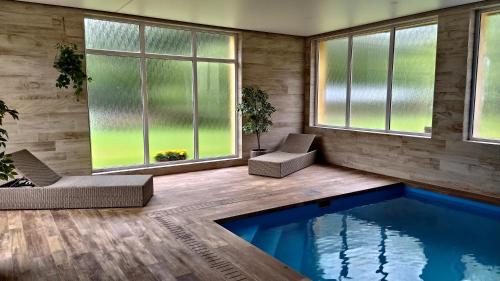 a living room with a swimming pool and windows at Penzion Bělidlo in Kunžak