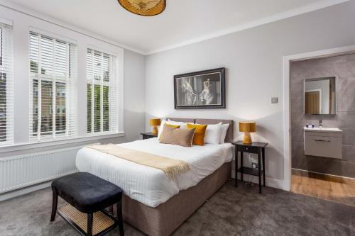 a bedroom with a large bed and two windows at Seafield House - Donnini Apartments in Ayr