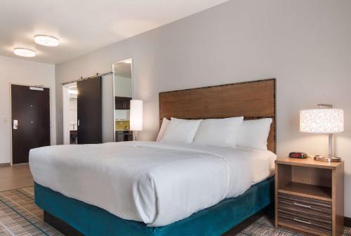 um quarto com uma grande cama branca e um espelho em MainStay Suites East Camden em Camden