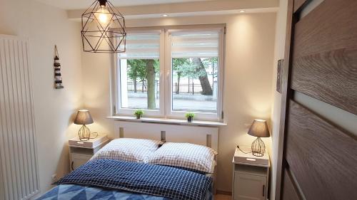 a bedroom with a bed and two night stands with lamps at Solano Apartments in Świnoujście