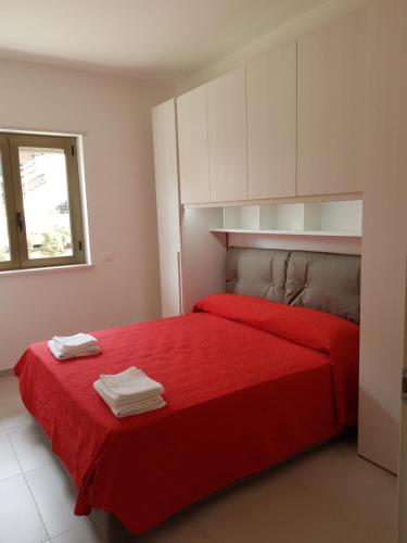 Appartamento Miele في زامبروني: غرفة نوم بسرير احمر مع دواليب بيضاء