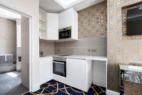a kitchen with white cabinets and a tv on the wall at Marble Arch Mews Apart'hotel in London