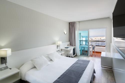Habitación blanca con cama y balcón. en Hotel Caserio, en Playa del Inglés