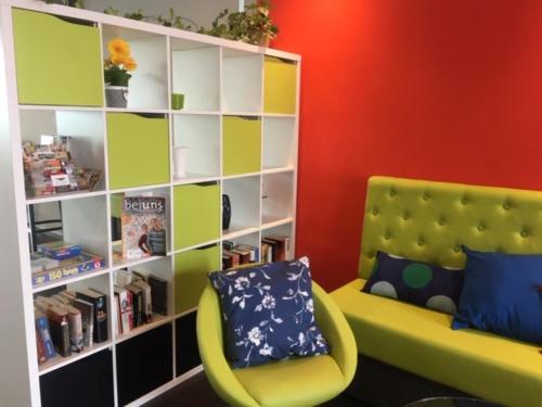 a room with a yellow chair and a book shelf at SleepySleepy Hotel Dillingen in Dillingen an der Donau