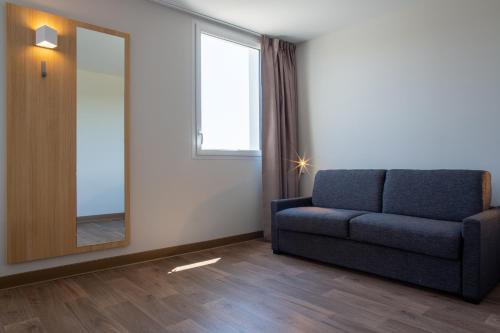 a living room with a couch and a mirror at B&B HOTEL Les Herbiers in Les Herbiers