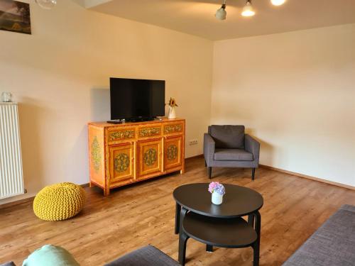 a living room with a tv and a chair and a table at Ferienwohnung MittagsSonne in Blaichach