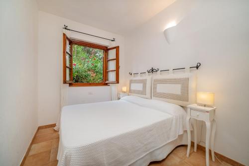 a white bedroom with a white bed and a window at 3BR Marina Apartment Porto Cervo in Porto Cervo