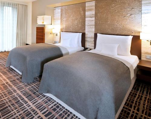 a hotel room with two beds in a room at Dorint Hotel am Heumarkt Köln in Cologne