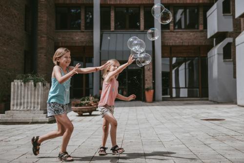 two young girls playing with bubbles on a street at Forest Hotel in Kraków