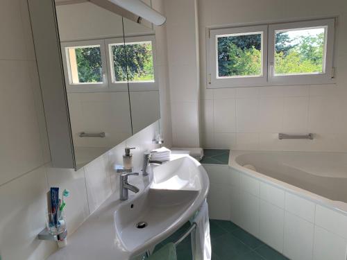 biała łazienka z umywalką i wanną w obiekcie Chambre D'Hôtes Wellingtonia w mieście Mont-sur-Rolle