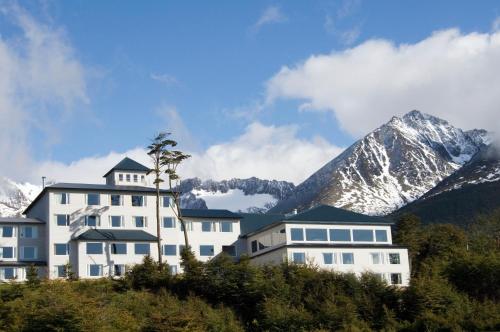 a large white building with a mountain in the background at Los Acebos Ushuaia Hotel in Ushuaia