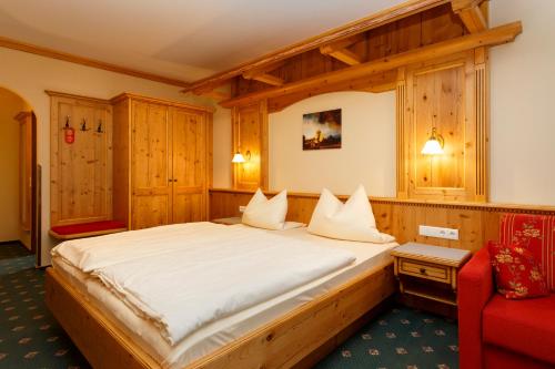 a bedroom with a large bed and a red chair at Hotel Gondel in Altenkunstadt