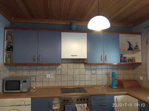 een keuken met blauwe en witte kasten en een licht bij Villa Alexandra in Iraklitsa