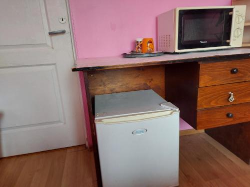 a small white refrigerator under a counter with a microwave at Отдельная комната в Юрмале in Jūrmala