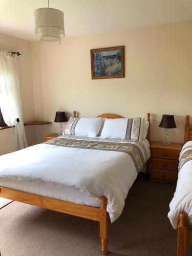 a bedroom with a large bed with white sheets at Elm Brook B&B in Ballyshannon
