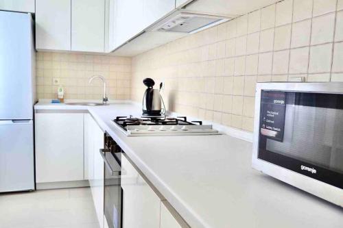 a kitchen with a stove and a tea kettle on a counter at White&Light flat near Gulliver in Kyiv