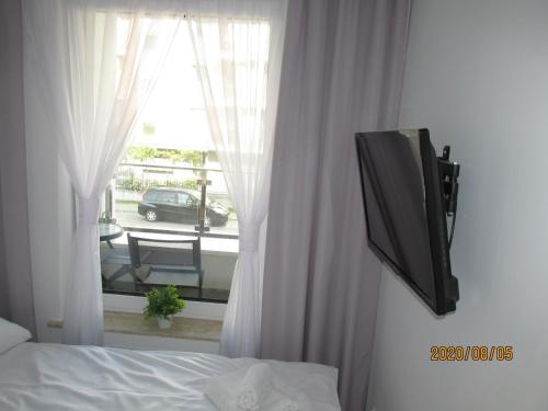 a bedroom with a tv and a bed and a window at Apartament Oskar in Kołobrzeg