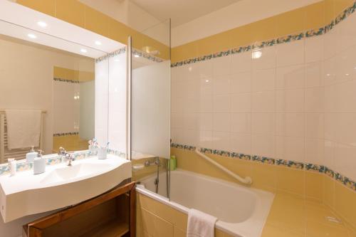 een badkamer met een wastafel, een bad en een spiegel bij Résidence Pierre & Vacances Le Mont Soleil in La Plagne