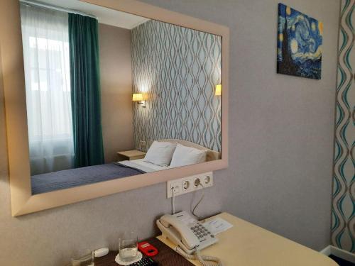 a bedroom with a mirror and a phone on a desk at Hotel Ajur in Odesa