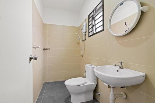 ein Badezimmer mit einem WC, einem Waschbecken und einem Spiegel in der Unterkunft Suraya Homestay Semi-D in Sepang