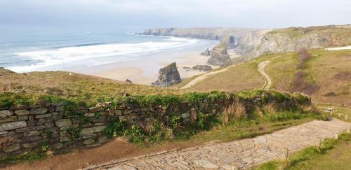 a stone wall next to a beach and the ocean at The Hideaway at Tregoose Old Mill in Newquay