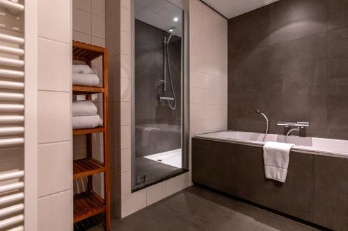 een badkamer met een bad, een wastafel en een douche bij Boshotel - Vlodrop, Roermond in Vlodrop