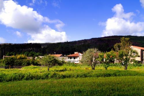 a field of grass with a house in the background at Espaciosa casa de aldea, arte y descanso in Fisterra