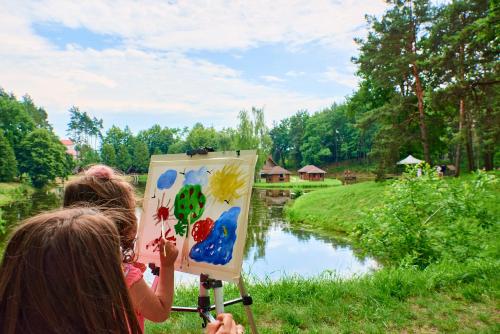 two girls are painting a picture of a river at Kryve Ozero in Novoyavorivsk