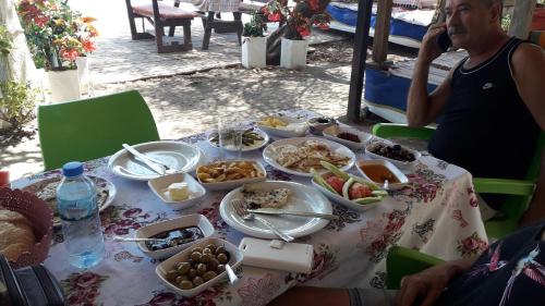 a man talking on a cell phone at a table with food at Caunos bungalow in Mugla