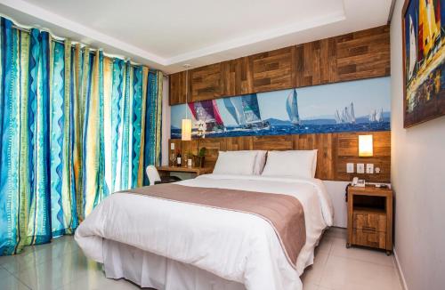 a bedroom with a large white bed and curtains at Hotel Ilhabela in Ilhabela