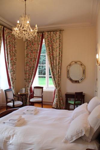 a bedroom with a white bed and a chandelier at Château de Lannouan in Landévant