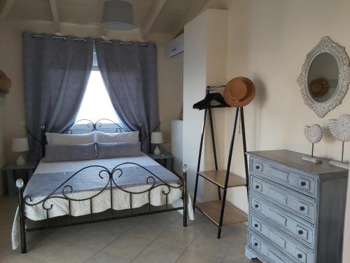a bedroom with a bed and a dresser and a window at Le Grand Bleu in Sitia