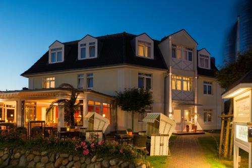 a large house with chairs and tables in front of it at Sylter Domizil in Wenningstedt