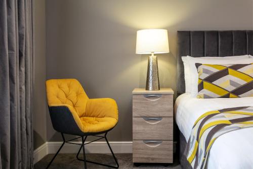 a bedroom with a bed and a chair and a lamp at Roydon Marina Village Hotel in Roydon