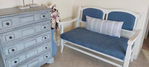 a bedroom with a white dresser and a blue chair at Le Grand Bleu in Sitia