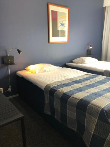 a bedroom with two beds with a plaid blanket at West Side Hotel in Turku