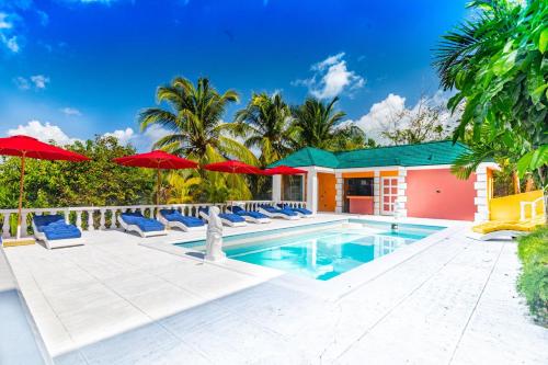 una piscina con tumbonas y sombrillas en Parrot Cottage at Viking Hill - Love Beach, en Nassau