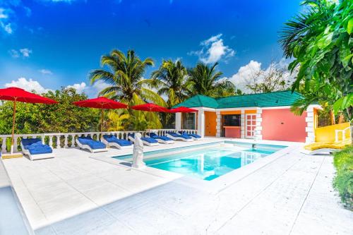a swimming pool with lounge chairs and umbrellas at Parrot Cottage at Viking Hill - Love Beach in Nassau