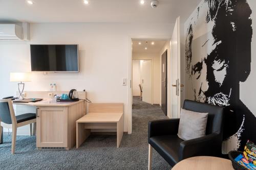 a living room with a desk and a chair at Hotel Deutscher Hof in Kassel