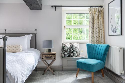 a bedroom with a bed and a blue chair at The Hideaway at Tregoose Old Mill in Newquay